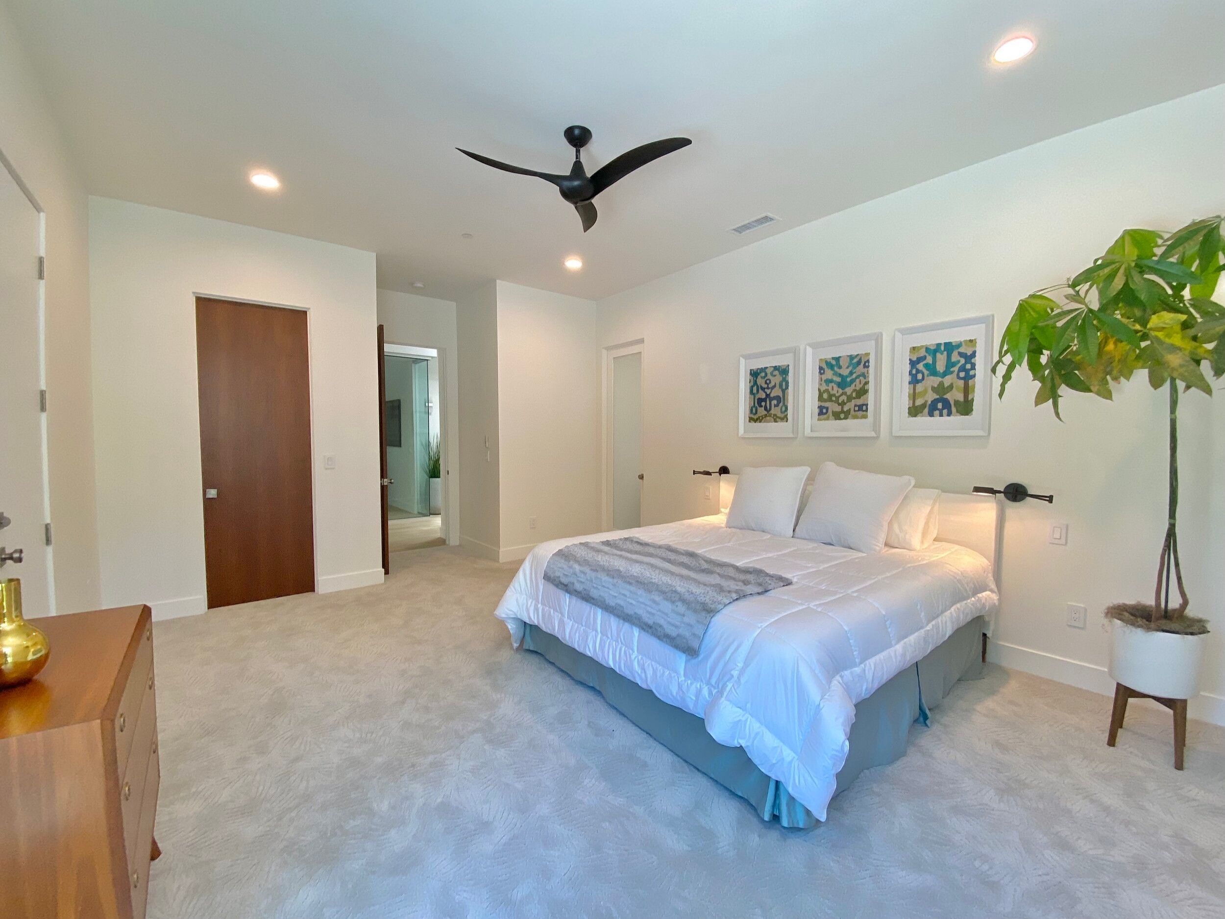 Bright bedroom with a ceiling fan, soft neutral finishes and garden-facing windows