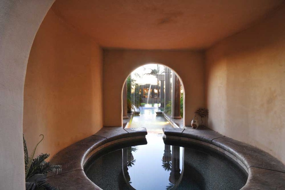 Arched passage with a water channel leading toward the pool